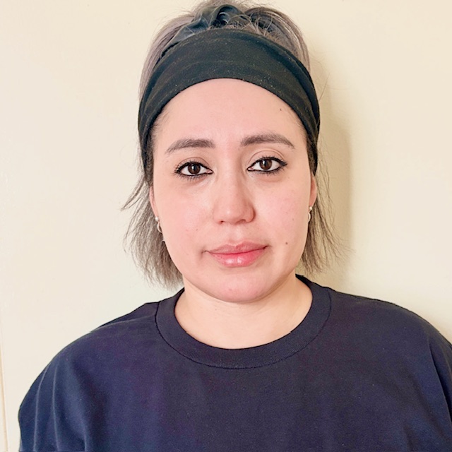 Portrait of a woman wearing a black headband and dark shirt, facing the camera with a neutral expression